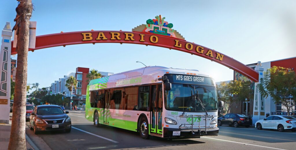 zero emissions bus passes under barrio logan sign